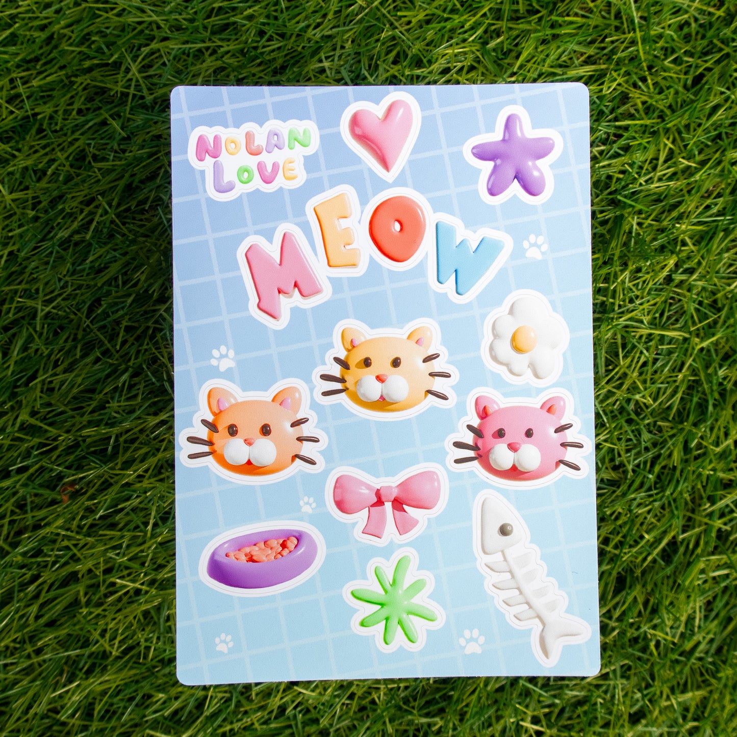 Sheet of colorful stickers with cat-themed designs on a grass background