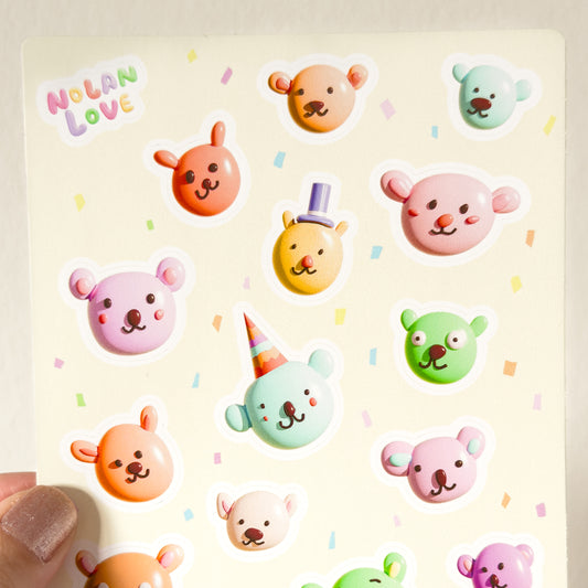 Close up of a sheet of colorful bear stickers held by a hand on a light background.