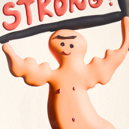 A close up of an art print with a cartoon character lifting weights and the word 'STRONG!' on a plain background.