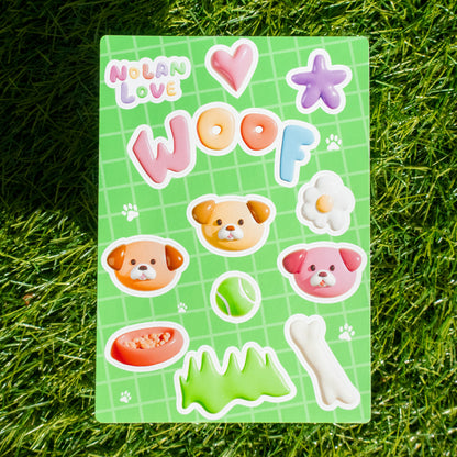 Sheet of colorful stickers with dog-themed designs on a green grid background, placed on grass.