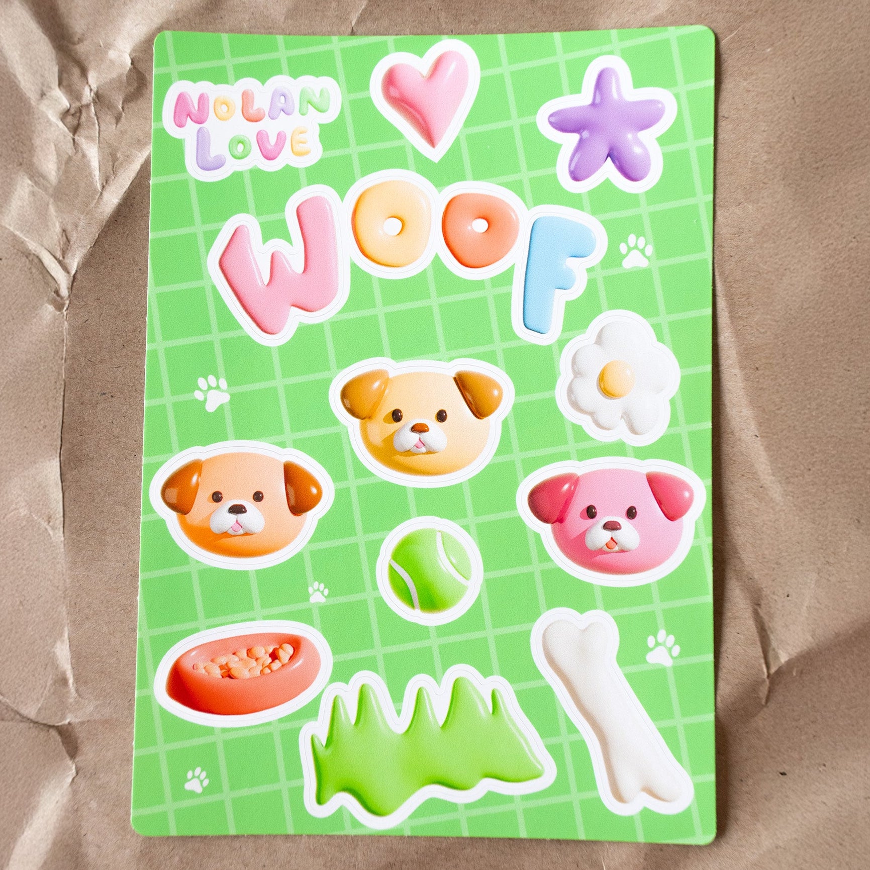 Sticker sheet with dog-themed designs on a green background, featuring the brand 'Nolan Love' on a crinkled brown paper background.
