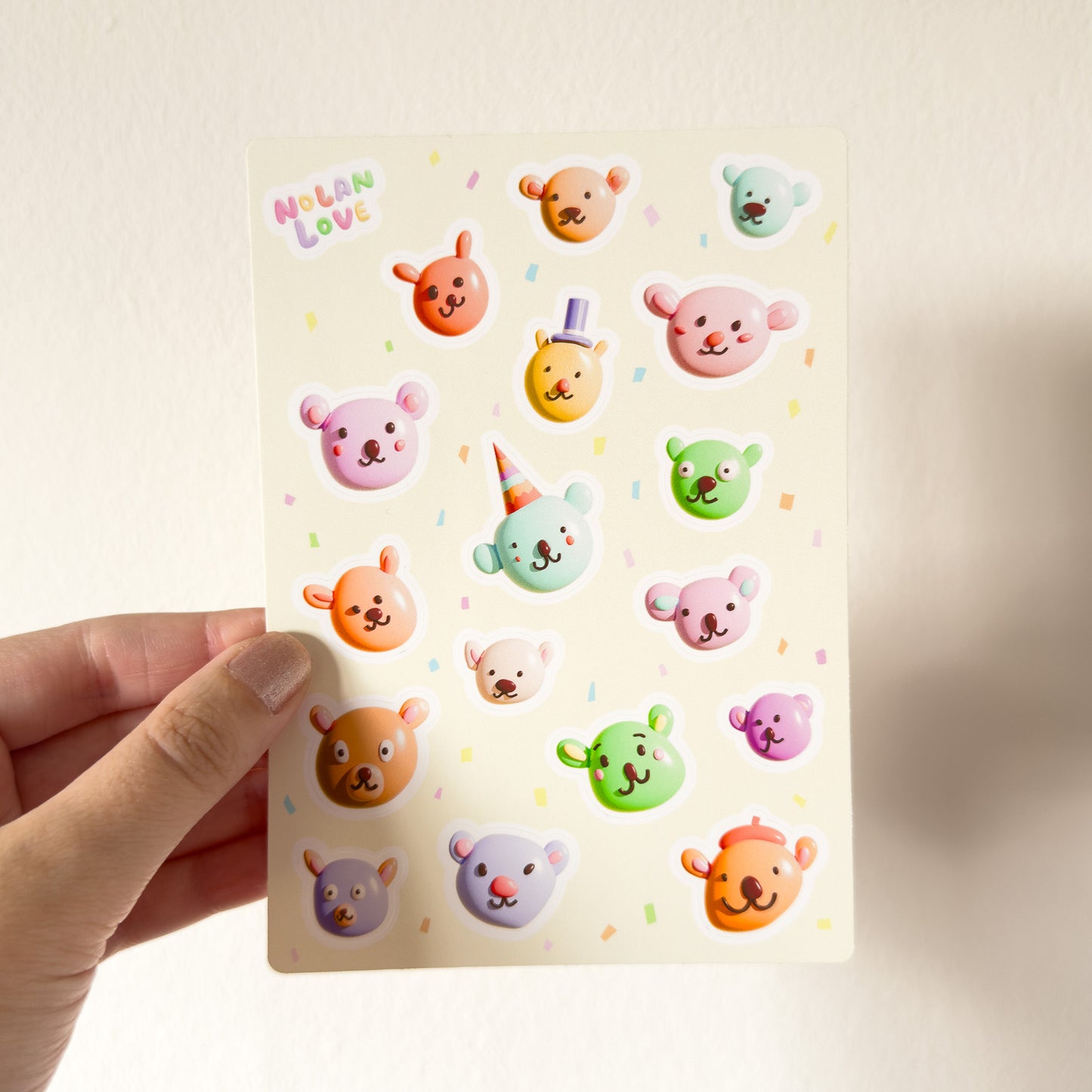 Sheet of colorful bear stickers held by a hand on a light background