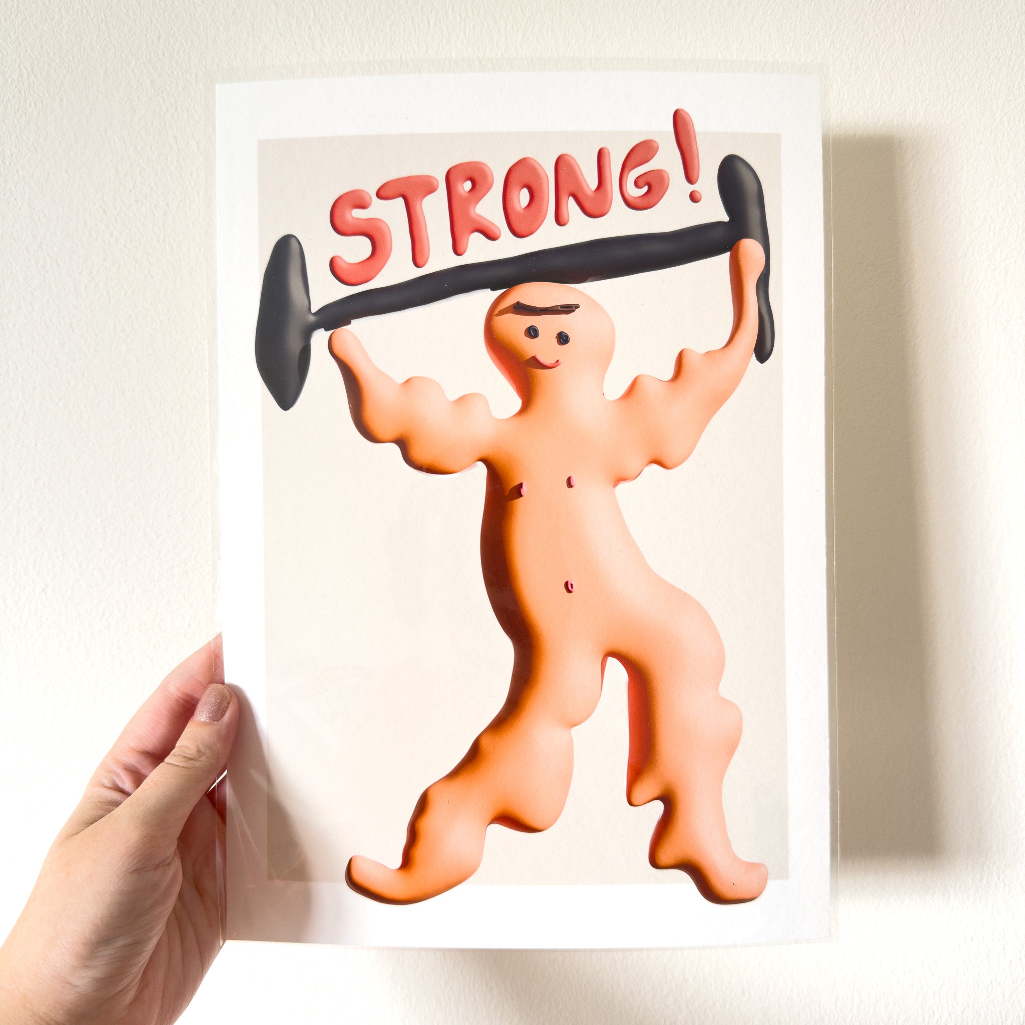 Art print with a cartoon character lifting weights and the word 'STRONG!' on a plain background
